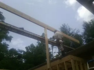 Carpenter setting a ridge beam over a new addition frame — Ice Dam Removal by Roofing Brothers in Le Claire