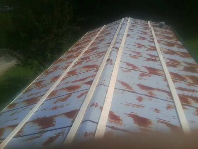 Rusted metal roof panels with new wood purlins before replacement — Storm Damage Roof Repair in Le Claire by Roofing Brothers