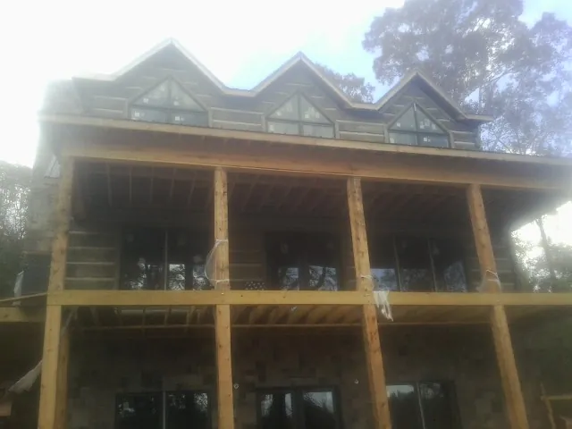 Dormers and porch framing on a large log home under construction — Roof Coating work by our crew in Le Claire