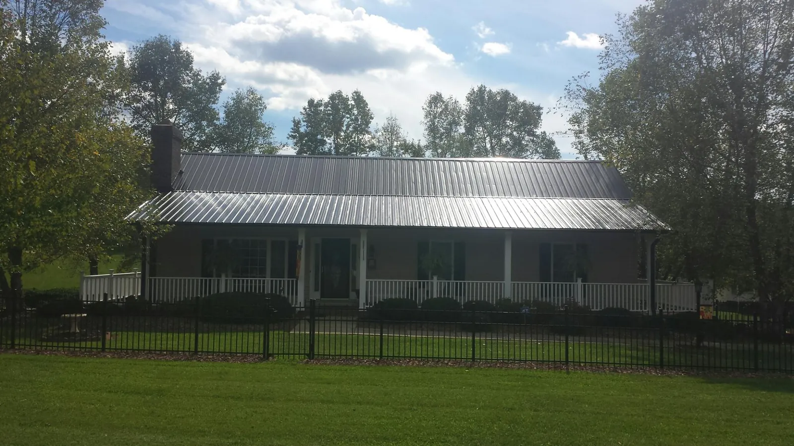Gray metal roof on a brick ranch with a full width front porch — Gutter Guard Installation work by our crew in Le Claire