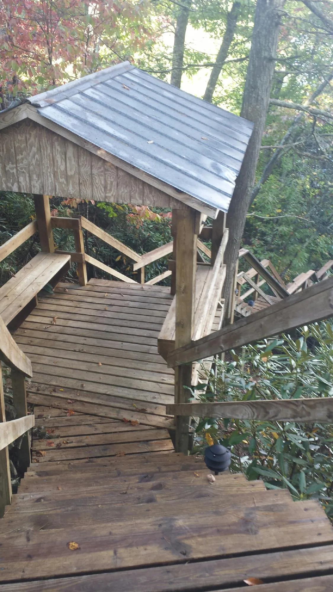 Metal roofed shelter over wooden steps on a wooded walkway — Skylight Repair & Installation work by our crew in Le Claire